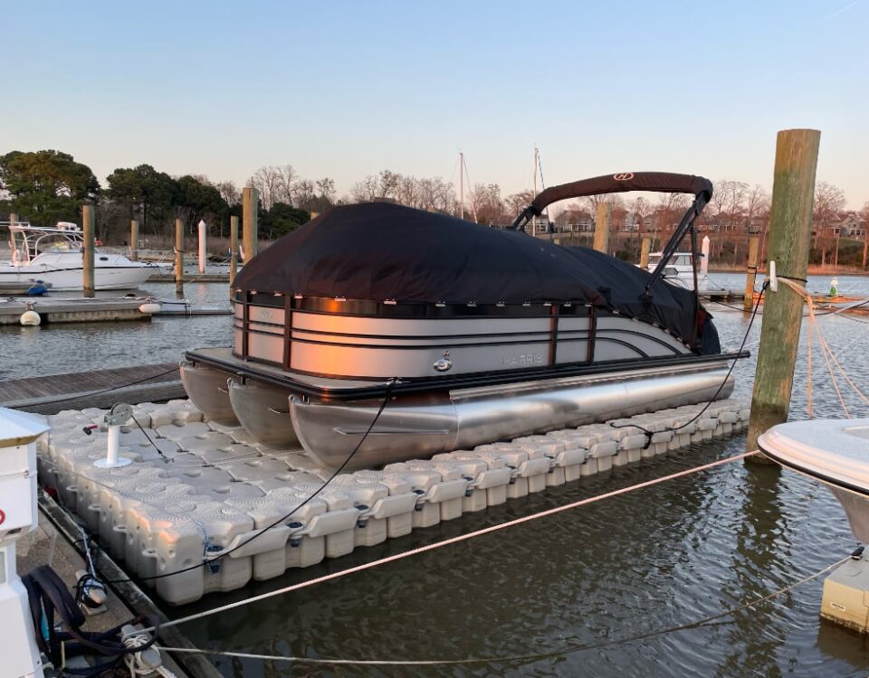 A covered pontoon boat on a floating dock.