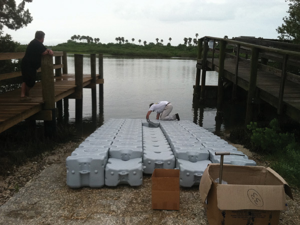 A man installing a dock ramp next to a lake.