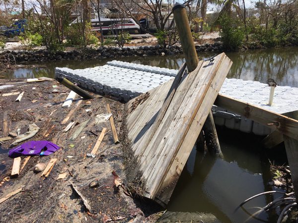 A torn-up wooden dock sits destroyed next to an intact Dock Blocks floating dock.