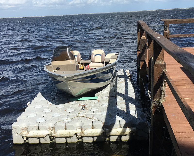 A small fishing boat on top of a floating dock in the ocean.