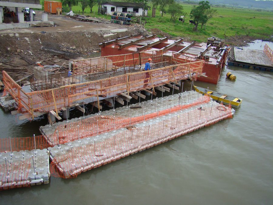 A construction crew using a floating dock to build above the water.