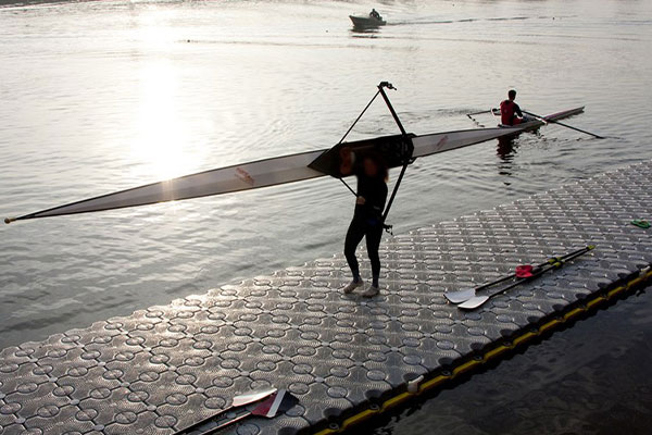 person holding rowboat walking on dock walkway
