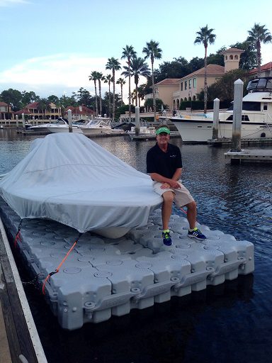 A man poses next to his covered boat on a completed floating dock.