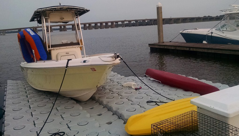 A boat with a floating raft sits on top of a floating dock in Key West.